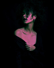 A creatively processed photo of a beautiful Afro-American girl with curly hair who poses in the studio on a dark background.