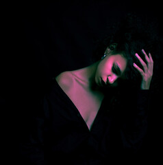 A creatively processed photo of a beautiful Afro-American girl with curly hair who poses in the studio on a dark background.