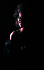 Fototapeta na wymiar A creatively processed photo of a beautiful Afro-American girl with curly hair who poses in the studio on a dark background.