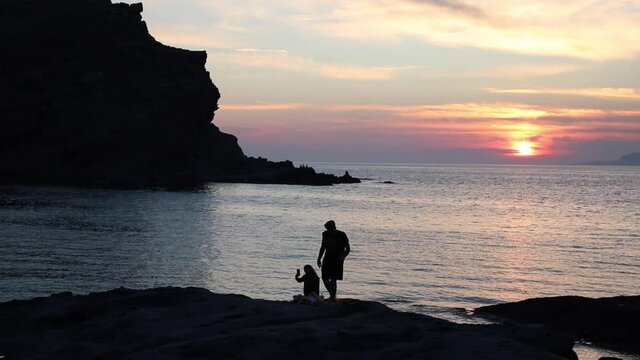 Fascinating island view at sunset with romantic couple 
 silhouette on rocks