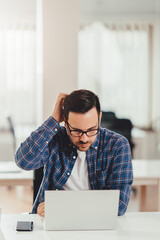 Businessman working in office and scratching his head
