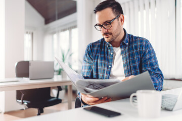 Fototapeta premium Young businessman doing paperwork in the office