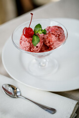 Raspberry sorbet in glass serving dishes and peppermint leaf inside transparent glass
