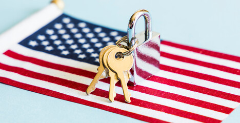 Metal silver padlock and keys with flag of the United States of America on blue background. 