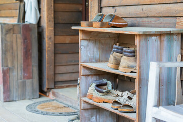 Fototapeta na wymiar Wooden shelves in front of the house on the farm in which there are old shoes