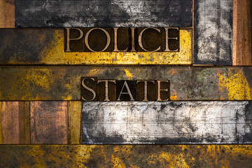 Photo of real authentic typeset letters forming Police State text on vintage textured silver grunge copper and gold background
