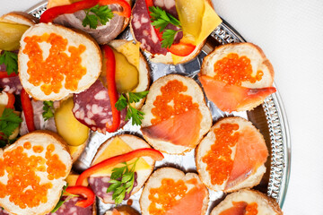 Delicious sandwiches with red fish and salmon caviar and herbs, there are sandwiches with sausage. Flat lay
