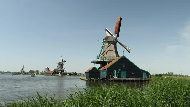 Windmills and farmhouse by river in Holland, the Netherlands.