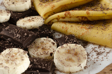 Closeup of sweet pancakes with banana and chocolate slices