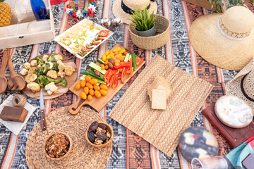 Beautiful summer picnic on the beach at sunset in zero waste style. Organic fresh fruit, cheese and vegetables on linen blanket. Eco friendly idea for weekend picnic. Top view.