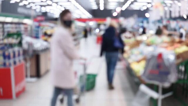 blurred background of a grocery hypermarket, people walk in masks coronavirus