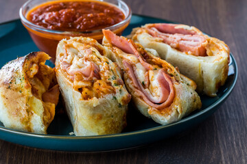 A close up view of pieces of Stromboli on a plate served with pizza sauce for dipping.
