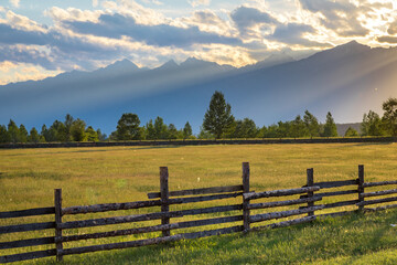 Obraz premium old wooden fence in the steppe on a background of mountains