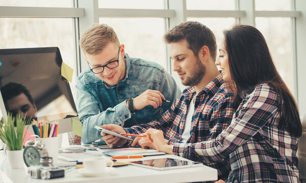 Side view of three creative designer artists working on computer at the office