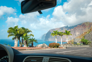 The view from the car in sunny weather on an empty road with palm trees, the ocean and the famous...
