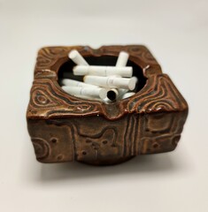 Brown ceramic ashtray with white cigarette butts