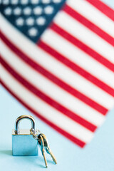 Metal silver padlock and keys with flag of the United States of America on blue background. 