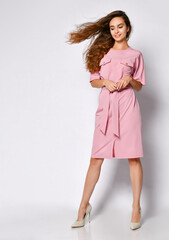 Full length portrait of happy beautiful woman in pink dress posing in studio isolated on white background