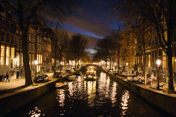 Fototapeta premium Characteristic view of a canal illuminated at dusk in Amsterdam city center. Netherlands, Holland, Europe.