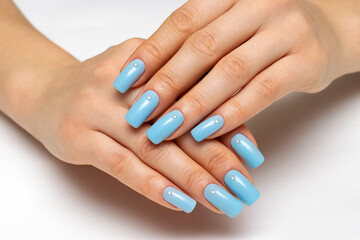 light blue manicure on square long nails with crystals on a white background close-up.