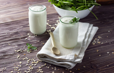 Natural yogurt in little jar with fresh mint leaves and bowl with salad. Healthy breakfast concept. Wooden background, close up.