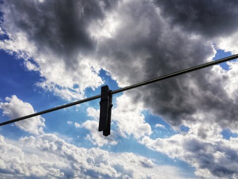 Clothespin hanging on the wire and cloudy sky