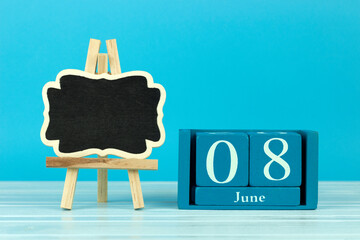 wooden calendar with the date of June 8 and an easel on a blue background, place for text, World Brain Tumor Awareness Day, World Oceans Day, International Housewife and Householder Day