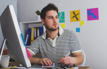 Young Handsome Graphic designer using graphic tablet to do his work at desk