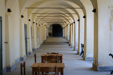 Fototapeta na wymiar Lungo porticato con tavolini in legno e chiavi trasversali sugli archi (Cinque terre, Liguria, Italia)