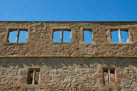 Facade of a brown castle wall, many beautiful windows to see, blue daylight shines through, filling the picture. Germany.