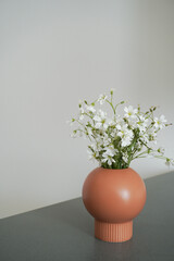 Soft home decor. Small white flowers in ceramic vases on table top. Front view composition with a space for a text. Eco decor