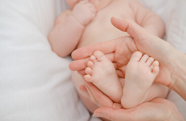 Obraz na płótnie Canvas Newborn baby Caucasian feet in mother's hands isolated on white background. Mom and her child. 