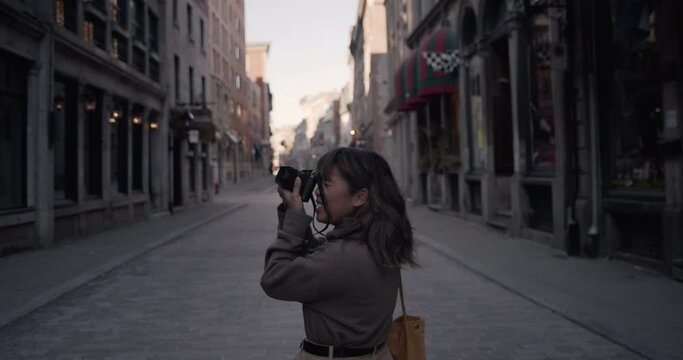 Street photographer looks around for a good photo opportunity smiling and happy takes photograph of cameraman reviewing image content with her shot