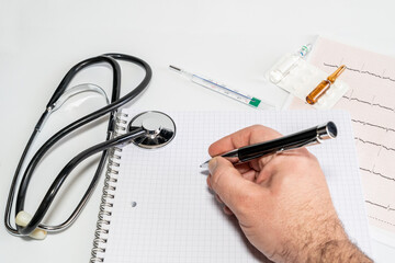 Hand of cardiologist doctor writing the diagnosis on block notes after seeing the electrocardiogram