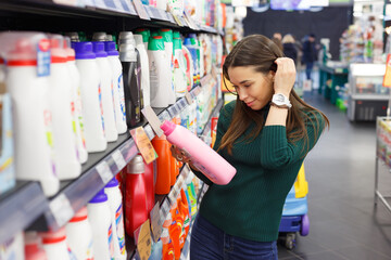 Woman choosing laundry detergent in grocery store.