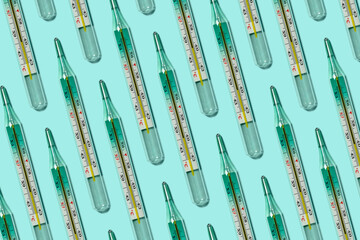 Medical mercury thermometers, colorful seamless pattern close-up, flat lay. Temperature is 39.9. Blue background.