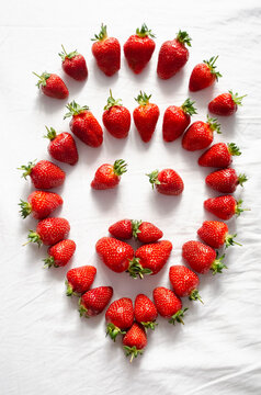Ripe strawberry berries are laid out on a white background in the shape of a smiley face