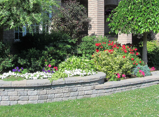 Landscape design with multiple levels and stone retaining wall for flower beds.