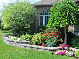 Landscape design with multiple levels and stone retaining wall for flower beds. - Powered by Adobe