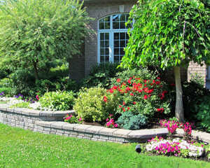 Landscape design with multiple levels and stone retaining wall for flower beds and hidden downspout...