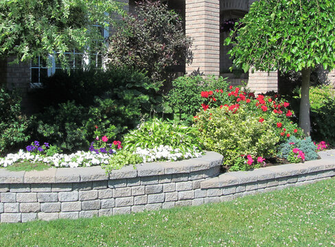 Landscape design with multiple levels and stone retaining wall for flower beds.
