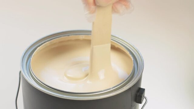 Stirring A Gallon Of Beige Paint With A Wooden Paint Stirring Stick Before Painting A Wall At Home DIY