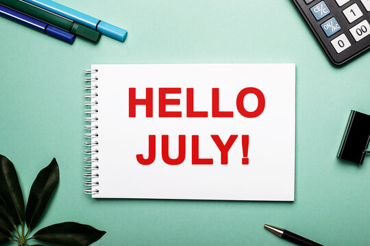 On a blue background next to a calculator, markers and a sheet of sheflera lies a notebook with the words Hello July