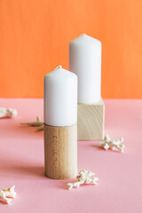 White aromatic candles on wooden stands with corals on pink and orange background. 