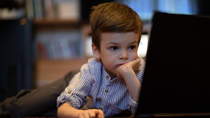 baby boy in blue shirt watching on laptop.