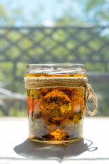 Labne balls with herbs and spices in a glass jar in the rays of the sun. Traditional yogurt cream cheese in the Middle East.