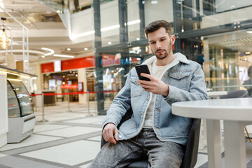 guy sitting at a table and looking at the phone