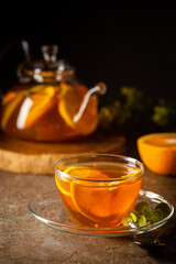 Glass teapot with hot citrus tea from oranges, lemons and limes, healthy drink on dark background