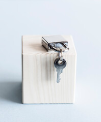 Silver shiny metal padlock with keys on wooden stand and blue background. 