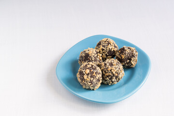 Five homemade energy balls on a blue plate. Healthy homemade chocolate dessert for Breakfast will fill you with energy